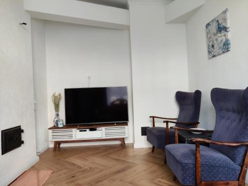 a living room with two blue chairs and a television at Esplanaadi Luxury Apartment in Pärnu