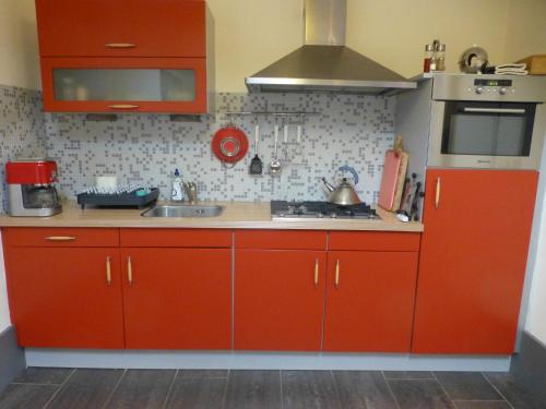 a kitchen with red cabinets and a sink at Vakantiehuis Onder de Peppel met sauna en jacuzzi in Wijk en Aalburg