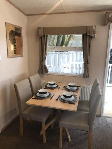 a dining room table with chairs and a window at Mudeford Beach Lodge in Mudeford