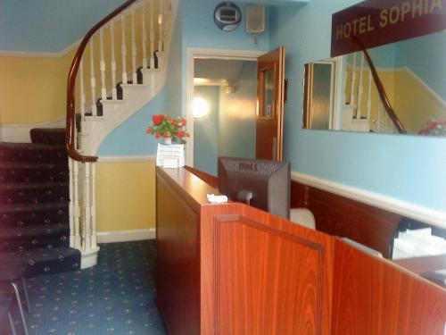 a hotel lobby with a staircase and a reception desk at Hotel Sophia in London