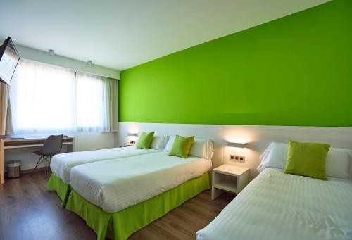 two beds in a room with a green wall at Hotel Julimar in Lloret de Mar