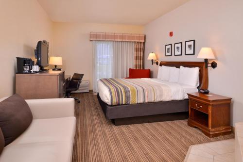 オマハにあるCountry Inn & Suites by Radisson, Omaha Airport, IAのベッドとソファのあるホテルの部屋