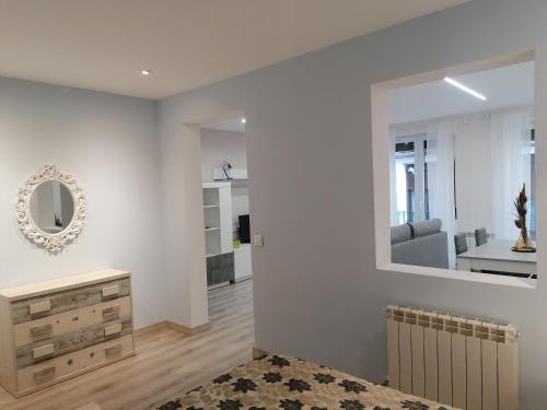 a living room with white walls and a mirror at Apartamentos El Cid in Molina de Aragón