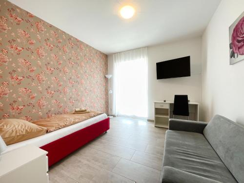 a bedroom with a bed and a couch and a tv at Pension Voesendorf in Vösendorf