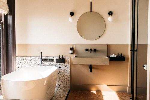 a bathroom with a tub and a sink and a mirror at Port Hotel in Eastbourne