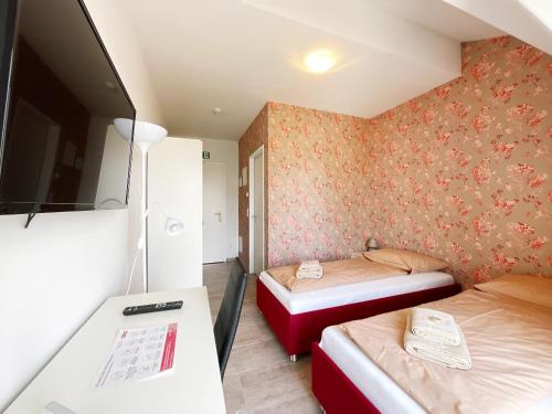 a small room with two beds and a table at Pension Voesendorf in Vösendorf