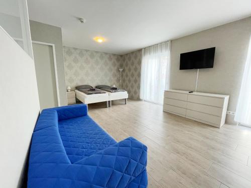 a living room with a blue couch and a television at Pension Voesendorf in Vösendorf