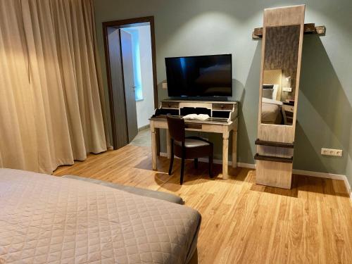 a bedroom with a desk with a television and a bed at Hotel Tortuga & Tex-Mex Bar & Grill in Grafenwöhr