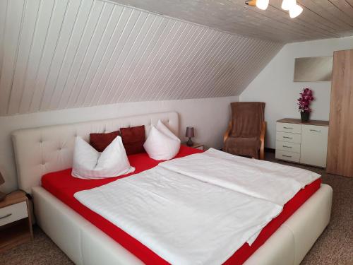 a bedroom with a white bed with red and white pillows at Ferienhaus Silke - östlich der Dorfstraße in Grieben Insel Hiddensee in Grieben