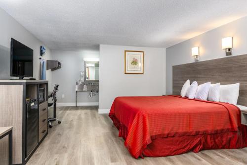 a hotel room with a red bed and a flat screen tv at Captains Quarters Motel & Conference Center in Eastham