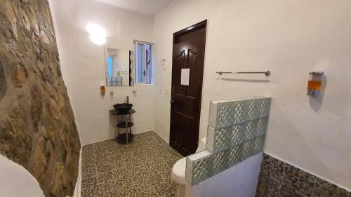 baño con aseo y puerta marrón en Hotel Quinto Sol, en Mazunte