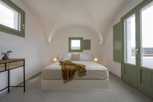 a white bedroom with a bed with a blanket on it at Oia Kissiri - Private Pool Villas in Oia