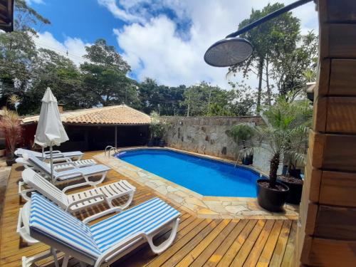 a swimming pool with lounge chairs on a wooden deck at Maré Leve Maresias in Maresias