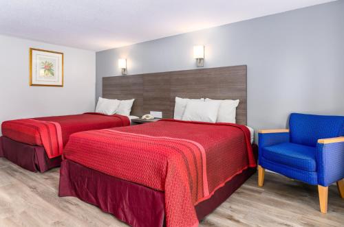 a hotel room with two beds and a blue chair at Captains Quarters Motel & Conference Center in Eastham