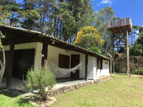 a house with a hammock on the side of it at Chalés Mathora in Visconde De Maua