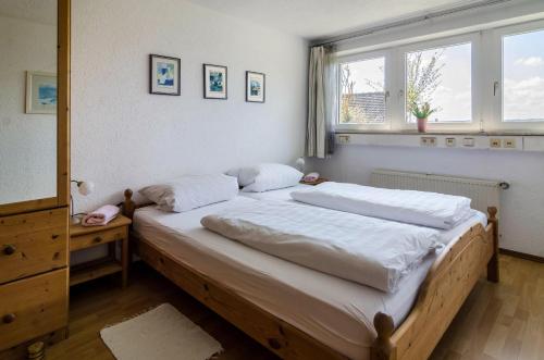 una camera da letto con un letto con lenzuola bianche e una finestra di Ferienwohnung Munding a Überlingen