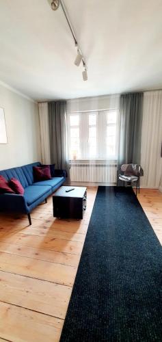 a living room with a blue couch and a black rug at Loft Rooms - Apartamenty w Kamienicy centrum, bezpłatny parking in Ełk
