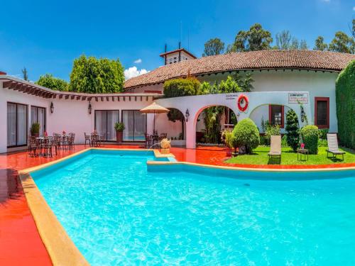 a villa with a swimming pool in front of a house at Best Western Plus Posada de Don Vasco in Pátzcuaro