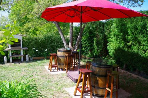 a red umbrella over a group of stools and barrels at Maison Elizondoa - chambres, restaurant et SPA in Masparraute