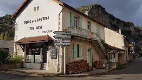 un antiguo edificio con letreros de la calle delante de él en Le Refuge du Cele, en Cabrerets