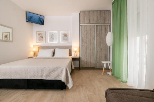 a bedroom with a large bed and a green curtain at Apartmani IVA in Neum