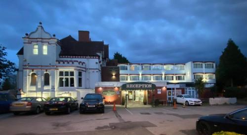 um grande edifício branco com carros estacionados num parque de estacionamento em Hylands Hotel em Coventry