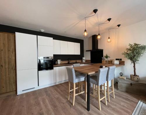 une cuisine avec une table en bois et des armoires blanches dans l'établissement Appartement tout confort haut de gamme en plein centre ville, à Gérardmer
