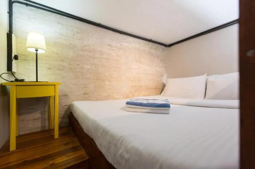 a small bedroom with a bed and a yellow table at Kim Haus Loft in George Town