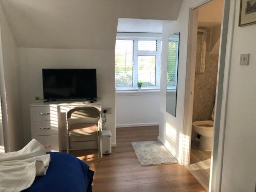 a bedroom with a television and a desk with a chair at Ponders End in Shide