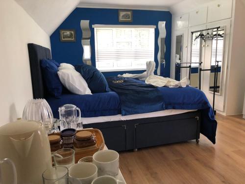 a blue bedroom with a bed and a table with glasses at Ponders End in Shide