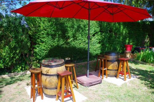 a red umbrella over a group of barrels and stools at Maison Elizondoa - chambres, restaurant et SPA in Masparraute