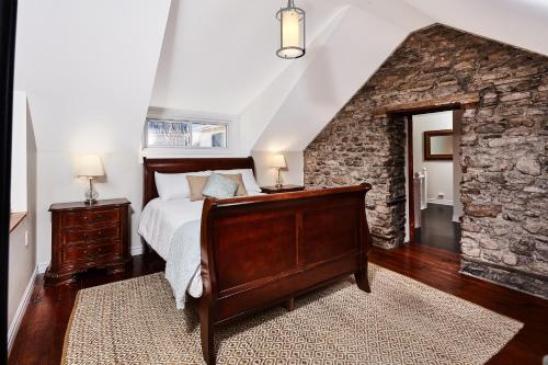 a bedroom with a bed and a stone wall at Arrowstone Farmhouse in Historic Old Town in Niagara on the Lake