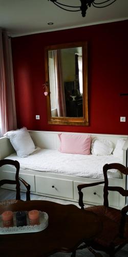 - un lit avec un miroir sur un mur rouge dans l'établissement La Cour du Puits, chambre Colyn, à Cormeilles