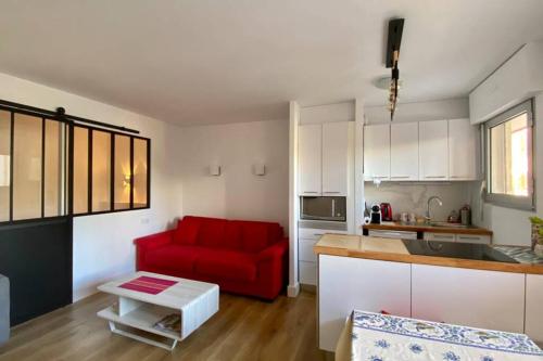 un salon avec un canapé rouge dans une cuisine dans l'établissement T2 Océan à 2 minutes à pied pour 4 + parking, à Biarritz
