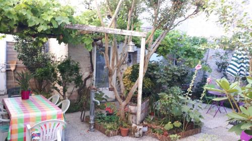 une table et des chaises dans un jardin avec un arbre dans l'établissement Arcade S, à Sainte-Marie de Ré