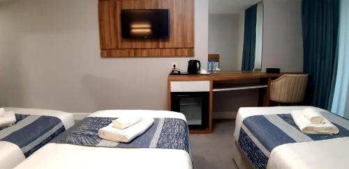 a room with three beds and a desk with a television at Old Batumi Hotel in Batumi