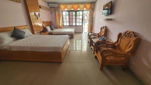 a bedroom with two beds and chairs and a television at Thành Mỹ Hotel in Cam Ranh