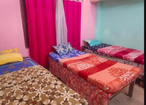 three beds in a room with colorful curtains at Traveller's Nest Homestay in Siliguri