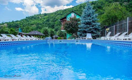 a large swimming pool with chairs and a building at Pension Charisma in Băile Herculane