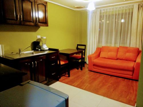 a living room with an orange couch and a kitchen at Casa de Huéspedes Tu Parada en Cuenca in Cuenca