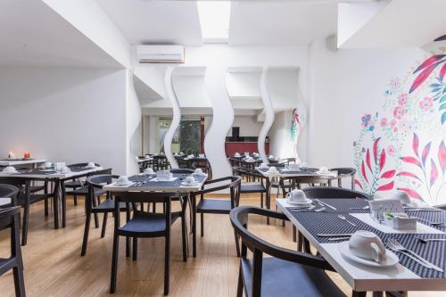 a dining room with tables and chairs and white walls at Hotel Florencia Plaza in Medellín