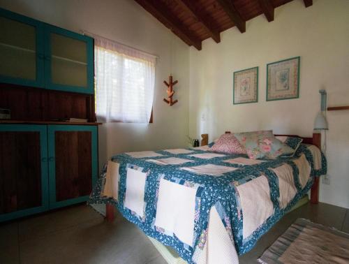 a bedroom with a bed with a blue and white blanket at Chalé Siriú - entre o rio e o mar in Siriú