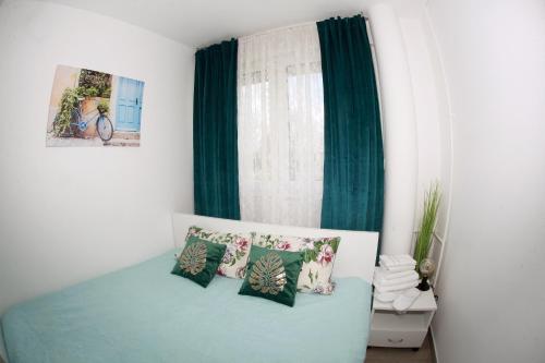 a bedroom with a bed with green curtains and pillows at Apartman Lucija in Karlovac