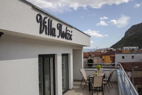 モスタルにあるVilla Hodžićのバルコニーにテーブルと椅子が置かれた建物