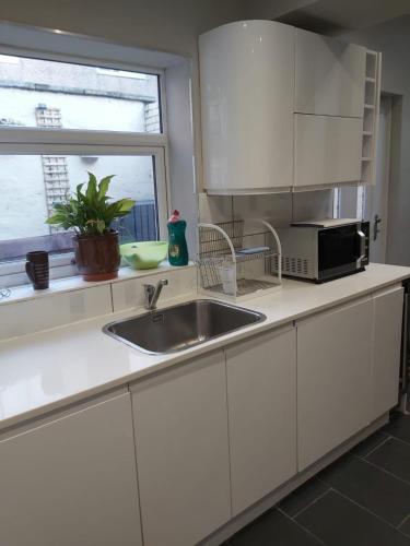a kitchen with a sink and a microwave and a window at Amble Holiday Home in Amble