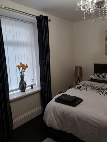 a bedroom with a bed and a vase with flowers in a window at Amble Holiday Home in Amble