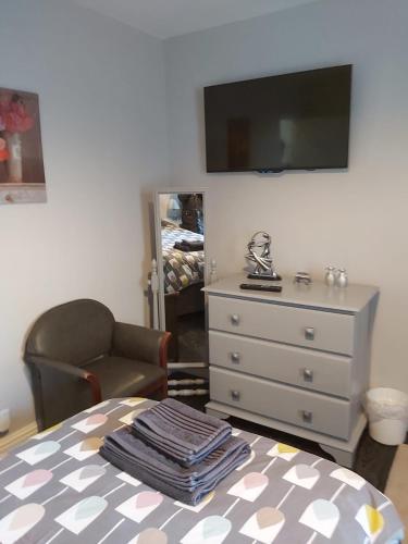 a room with a dresser and a chair and a table with towels at Amble Holiday Home in Amble