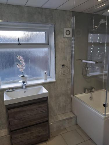 a bathroom with a sink and a tub and a window at Amble Holiday Home in Amble