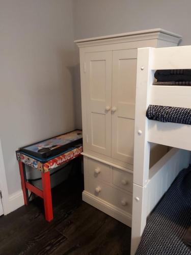 a bedroom with a bunk bed and a dresser with a stool at Amble Holiday Home in Amble