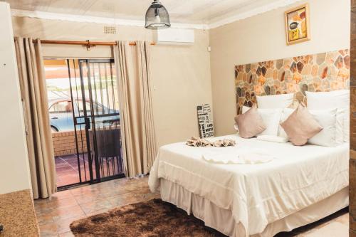 um quarto com uma grande cama branca e uma varanda em APICAL GUESTHOUSE em Maun